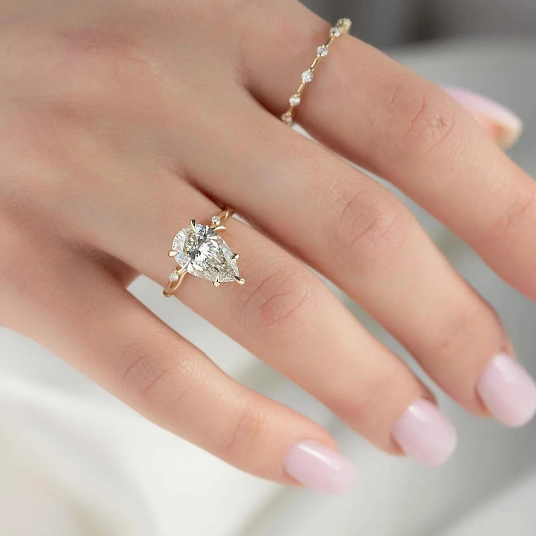 Three stone pear cut lab grown diamond engagement ring in yellow gold shown on the hand