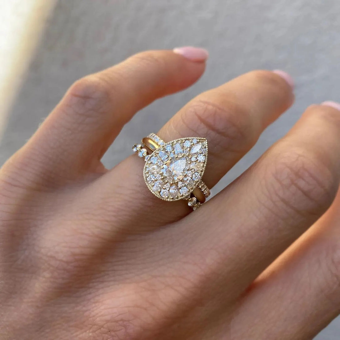 Vintage pear cut lab grown diamond cluster halo engagement ring in yellow gold on the hand