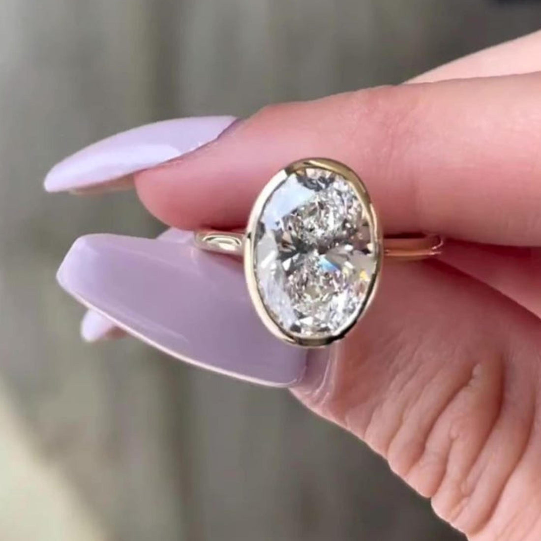 Oval cut lab grown diamond bezel set engagement ring with hidden halo