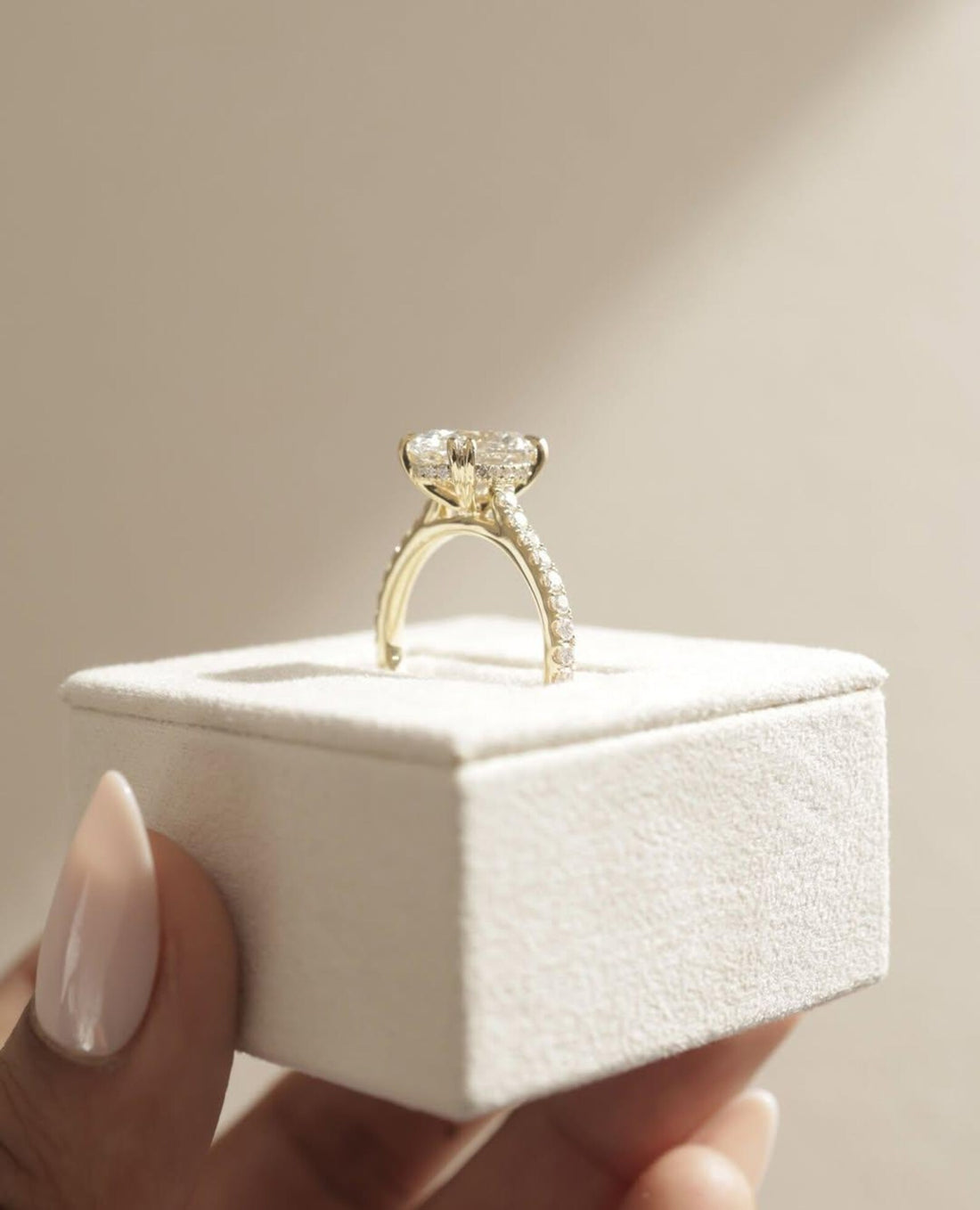 Oval cut lab grown diamond engagement ring with hidden halo on a pave eternity band in yellow gold, side profile