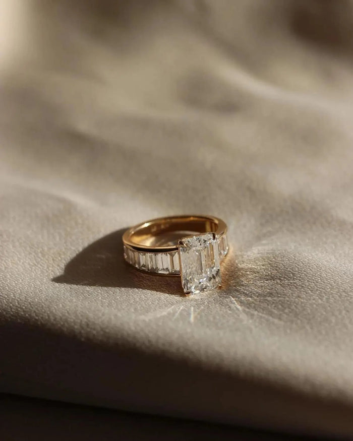 Emerald cut lab grown diamond engagement ring with channel set baguette shoulders in yellow gold