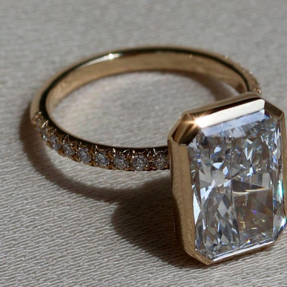 Radiant cut lab grown diamond bezel set engagement ring with pave band