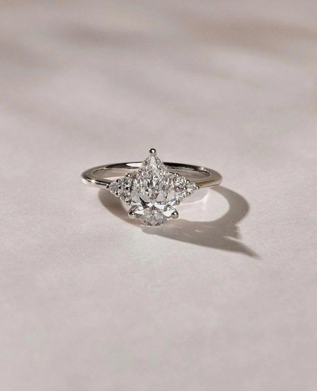 Three stone pear cut lab grown diamond engagement ring with trillion side stones in white gold