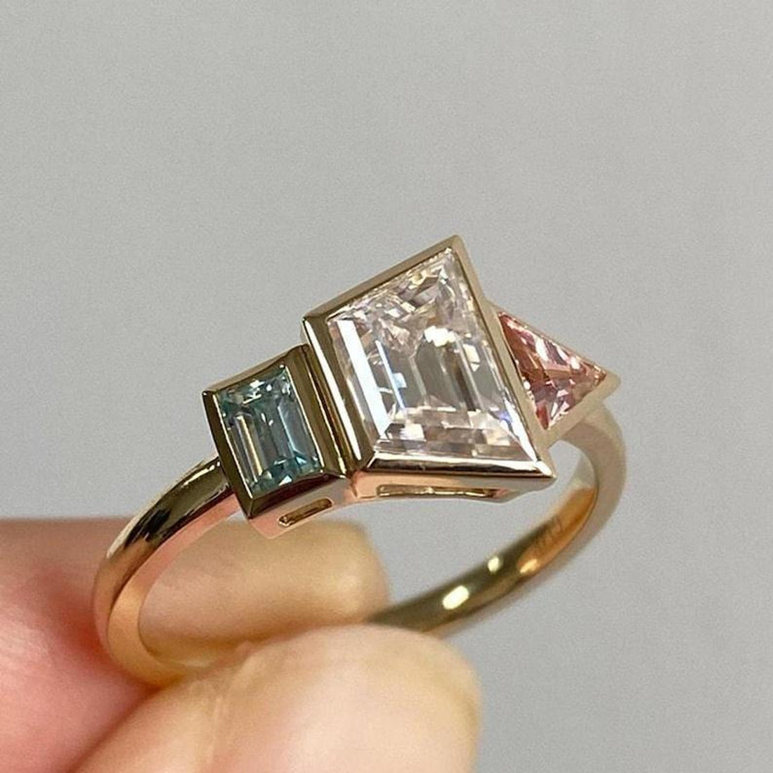 Trapezoid cut lab grown diamond three stone bezel engagement ring in yellow gold