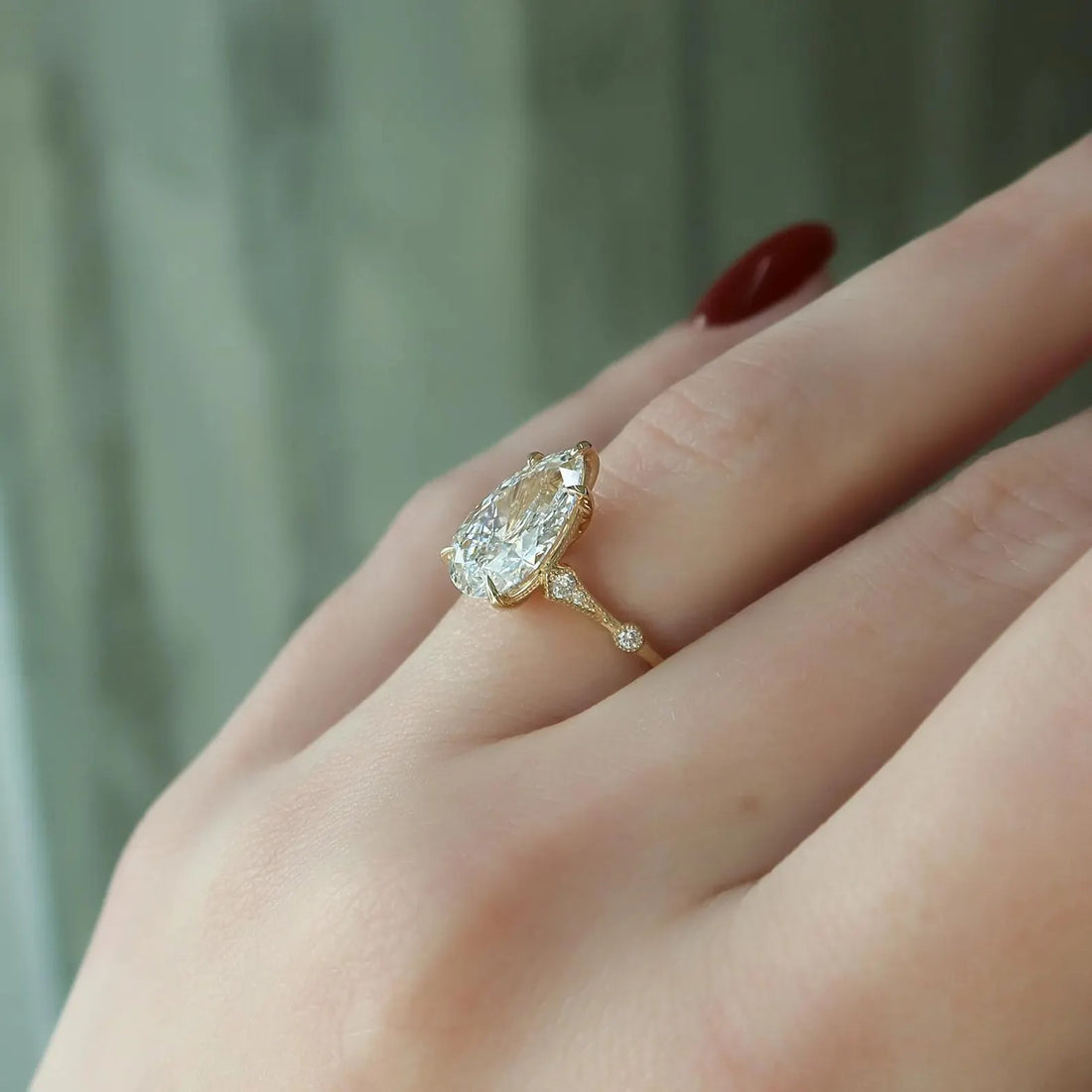 Elongated pear cut lab grown diamond halo engagement ring with accent band on the hand