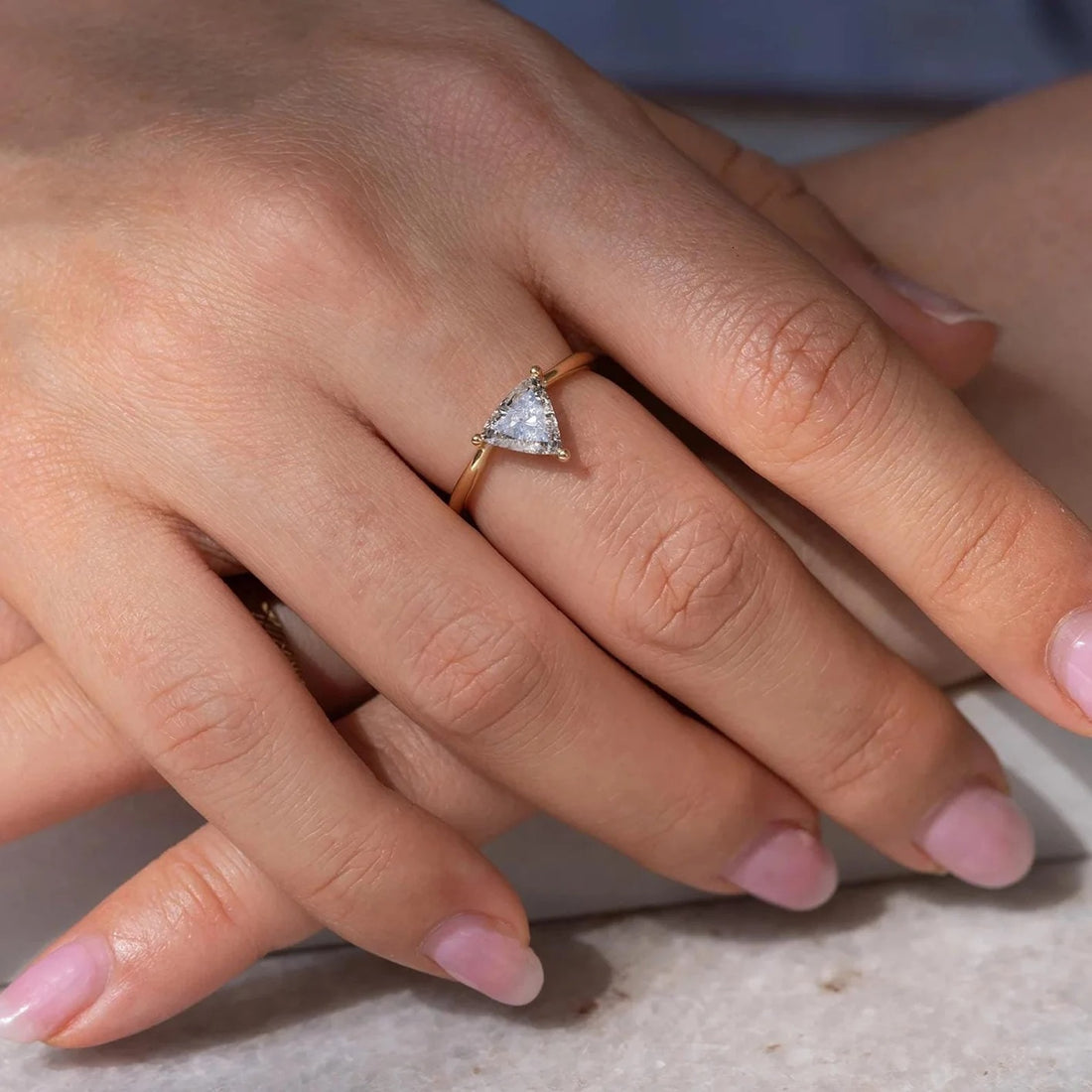 Trillion cut lab grown diamond solitaire engagement ring shown on the hand