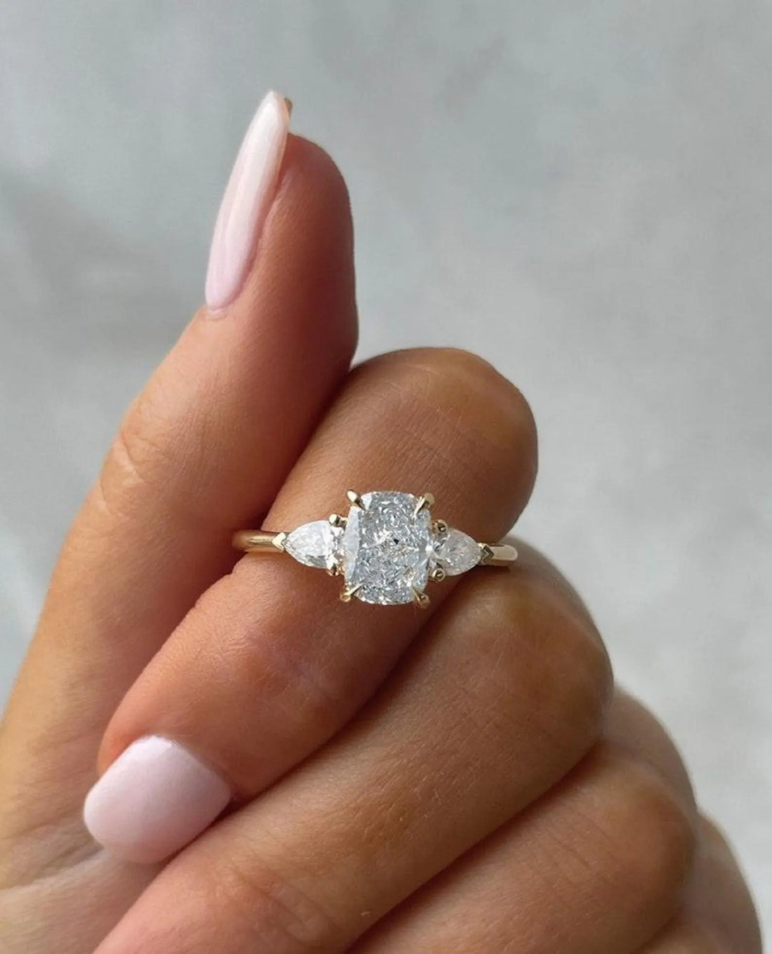 Cushion cut lab grown diamond three stone engagement ring with trillion side stones in yellow gold