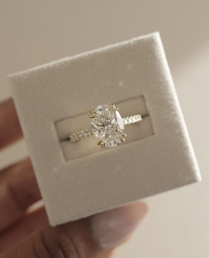 Oval lab grown diamond hidden halo engagement ring top view showing four prong setting and pave band
