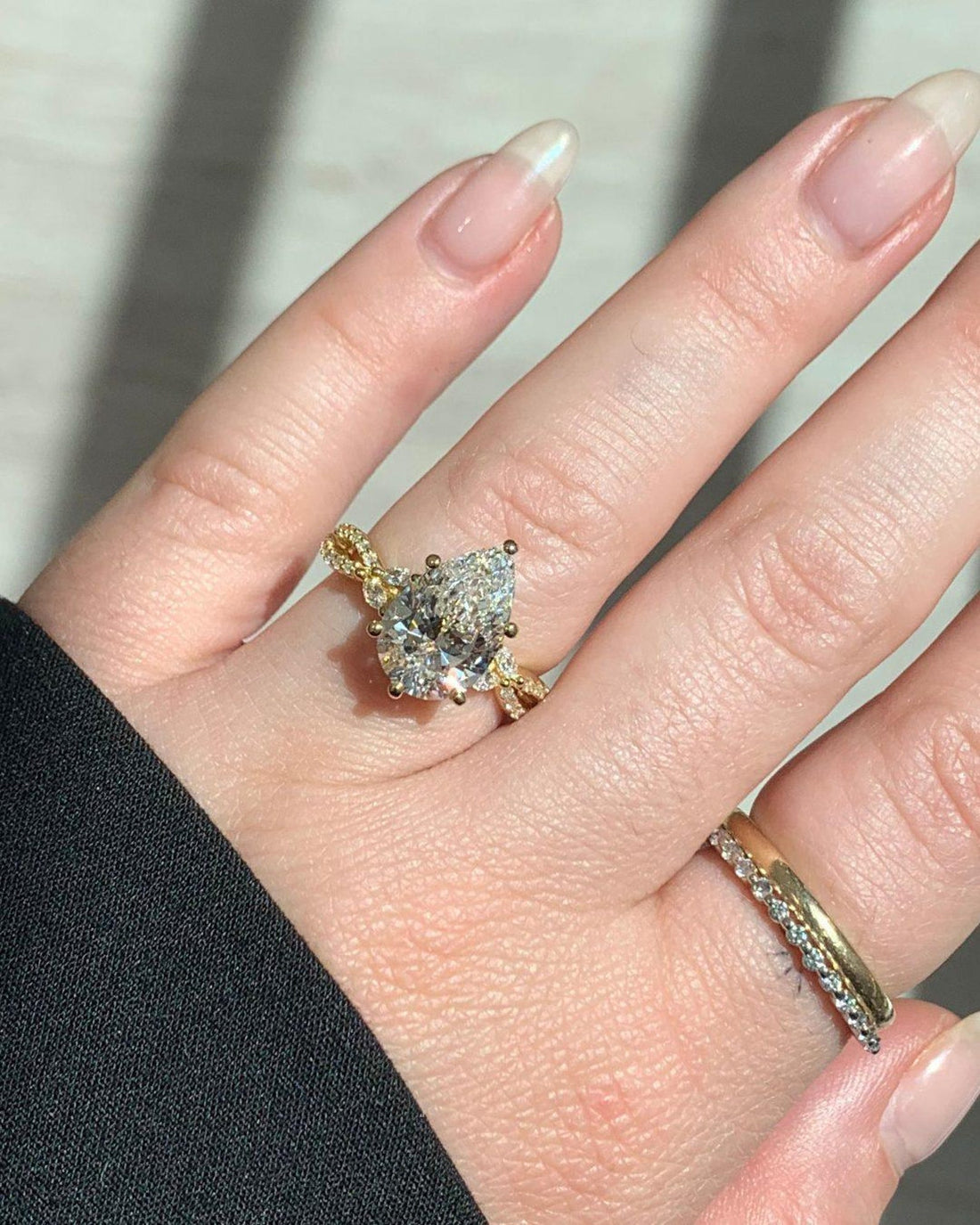 Pear cut lab grown diamond engagement ring with twisted vine band worn on hand