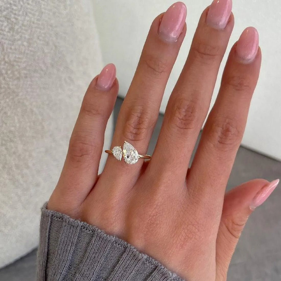 Toi et moi pear and round cut lab grown diamond engagement ring shown on the hand