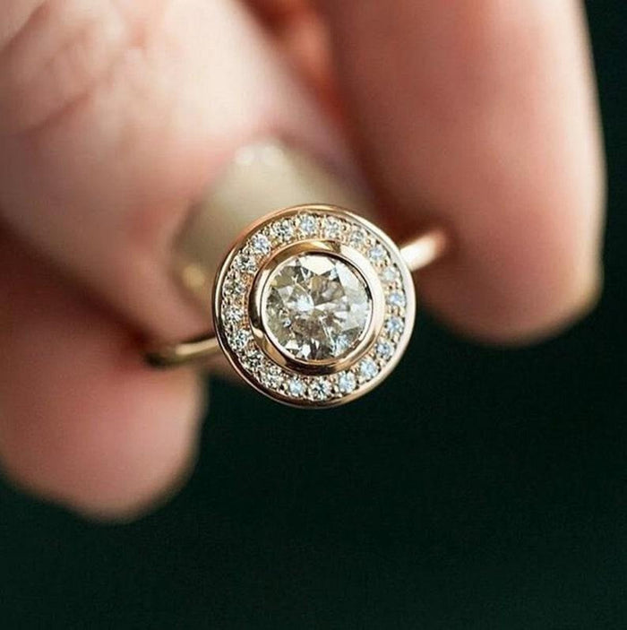 Bezel rim enclosing the round centre stone and its halo of accents