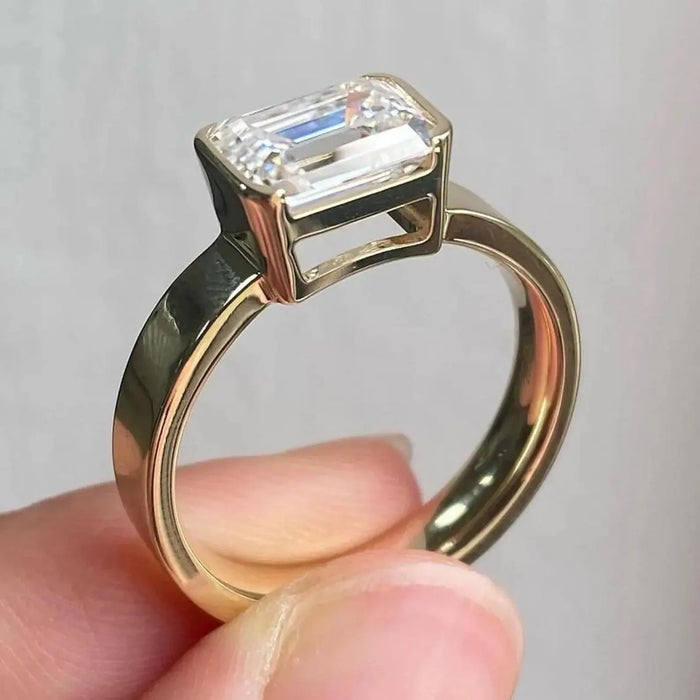Emerald cut lab grown diamond set east west across a wide band, angled view