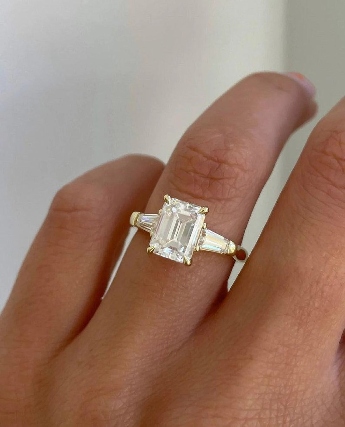 Emerald cut lab grown diamond three stone engagement ring with tapered baguettes in yellow gold