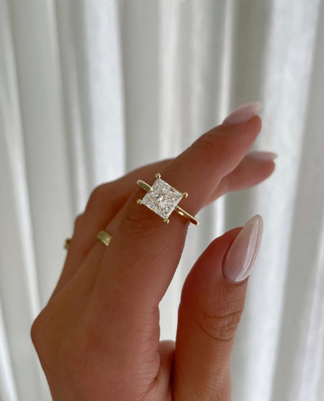 Princess cut lab grown diamond engagement ring with cathedral setting in yellow gold, worn on the hand