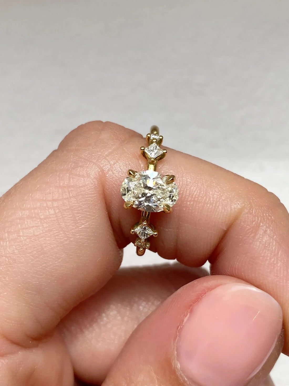 Oval cut lab grown diamond engagement ring with princess cut accents in yellow gold
