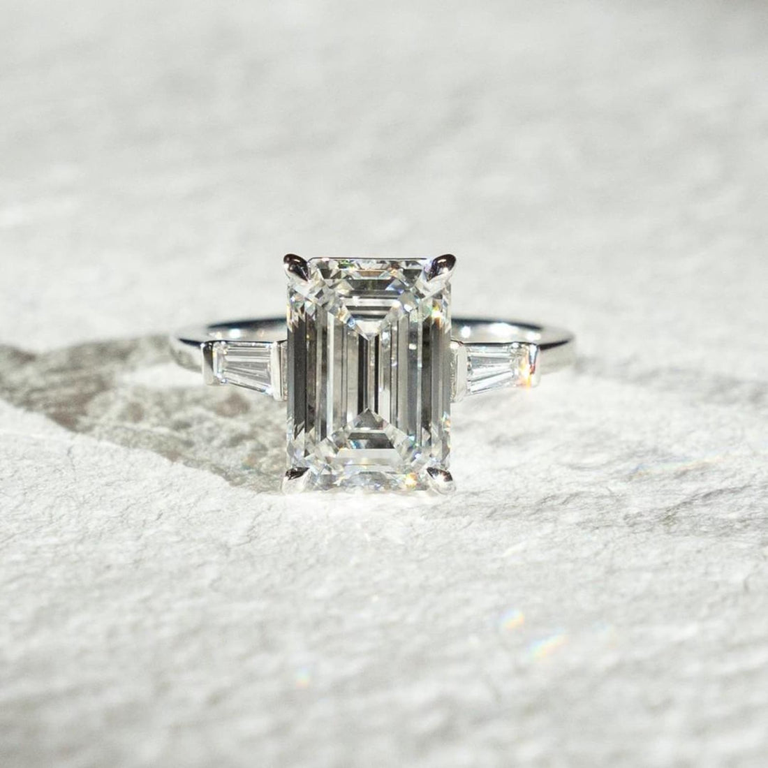 Tapered baguette side stones angled toward the emerald cut center diamond
