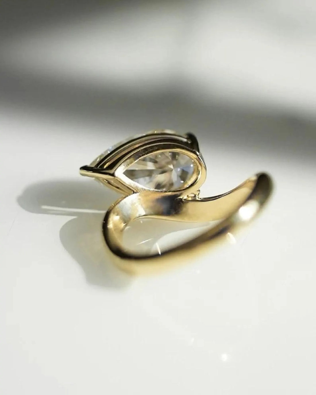 East west oval cut lab grown diamond ring with sculptural bypass band in yellow gold