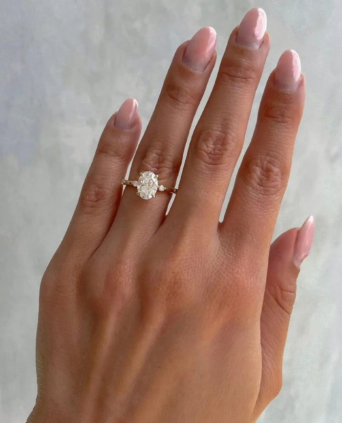 Oval cut lab grown diamond ring shown on the hand with spaced accents