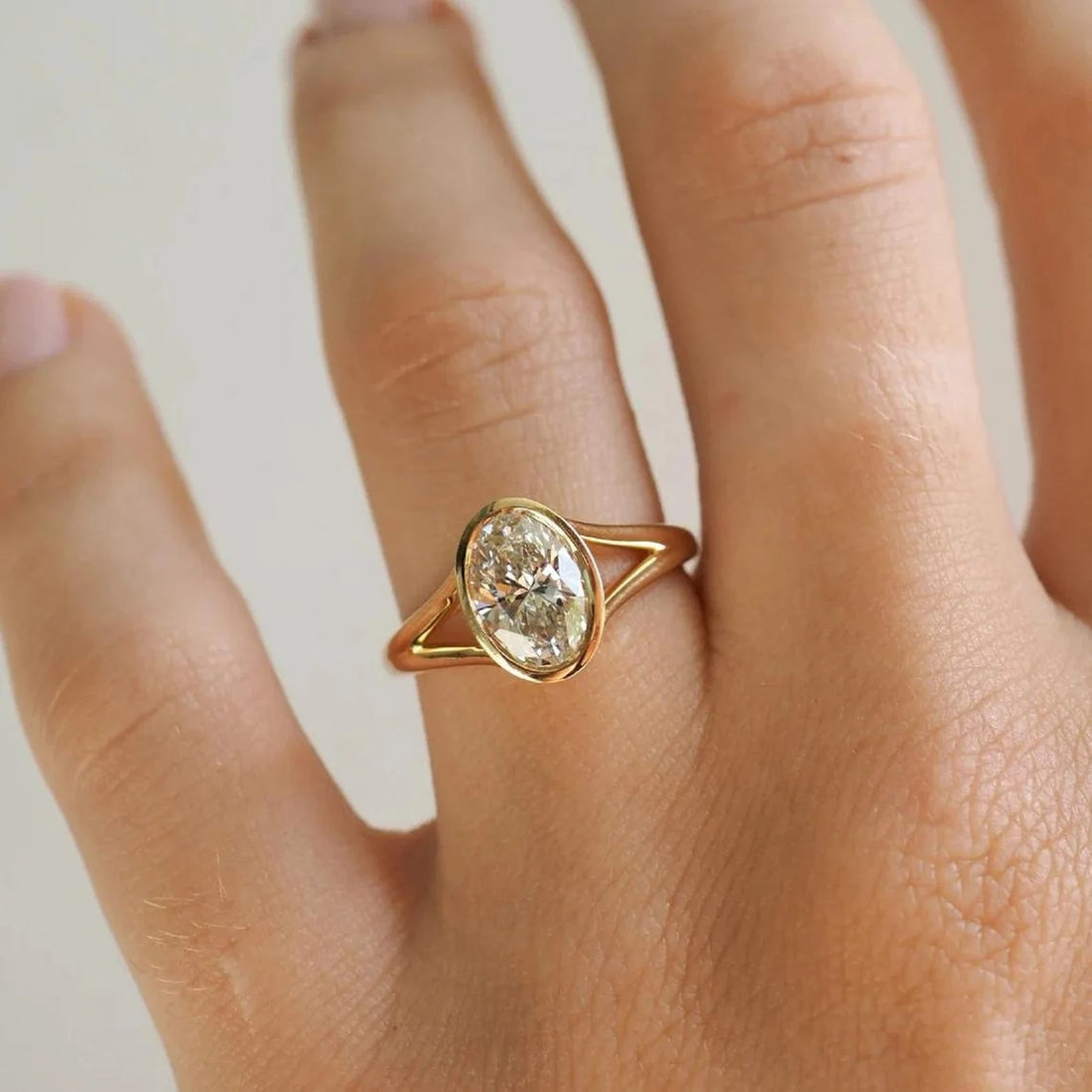 Bezel set oval cut lab grown diamond ring with split shank in yellow gold