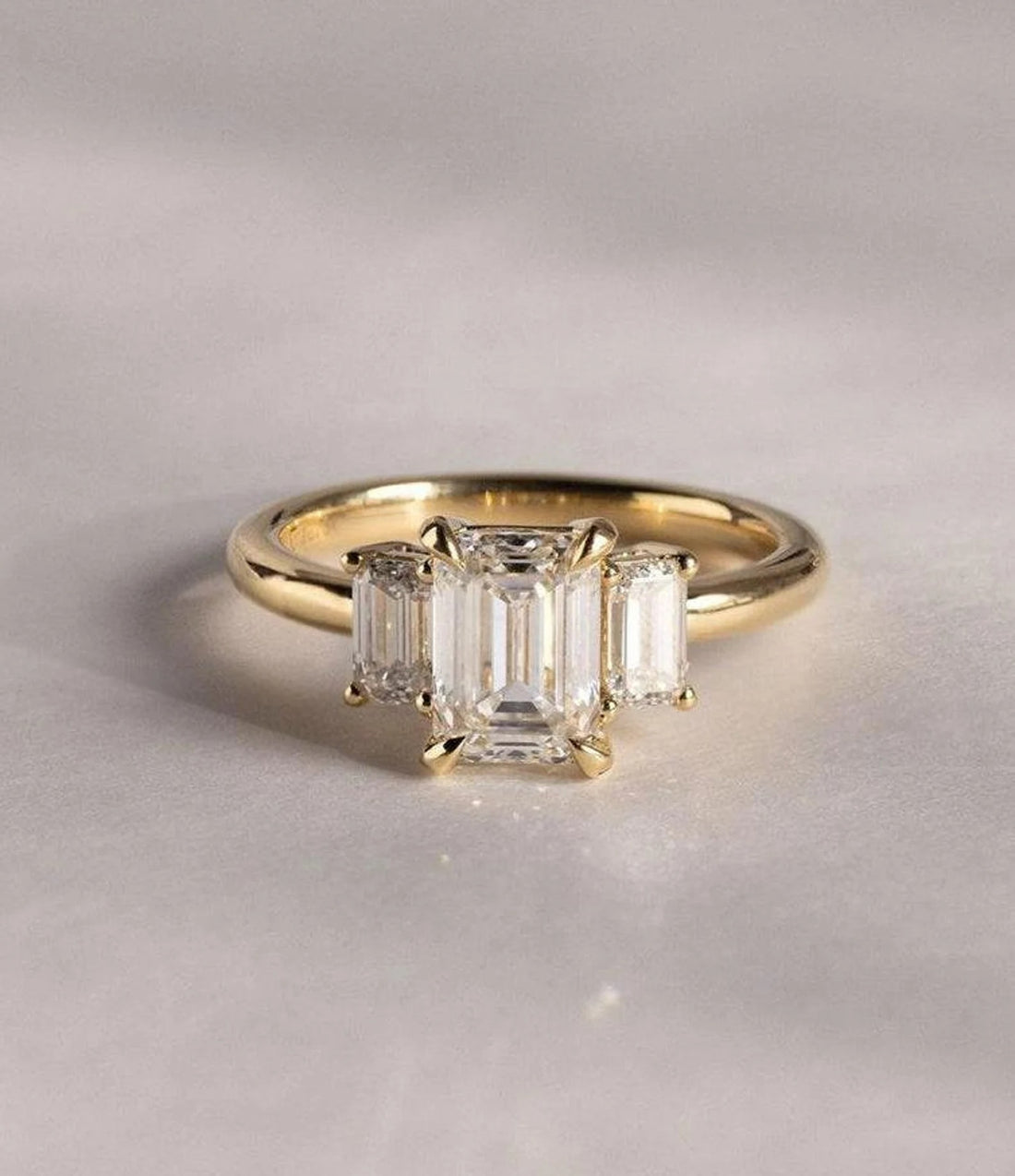 Emerald cut lab grown diamond three stone engagement ring with emerald cut side stones in yellow gold