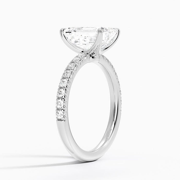 Profile view showing the bare open basket under the emerald cut and U set pave along the band