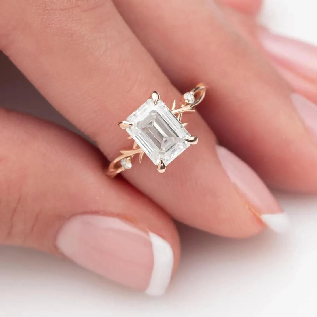 Emerald cut lab grown diamond engagement ring with twisted vine band shown on the hand