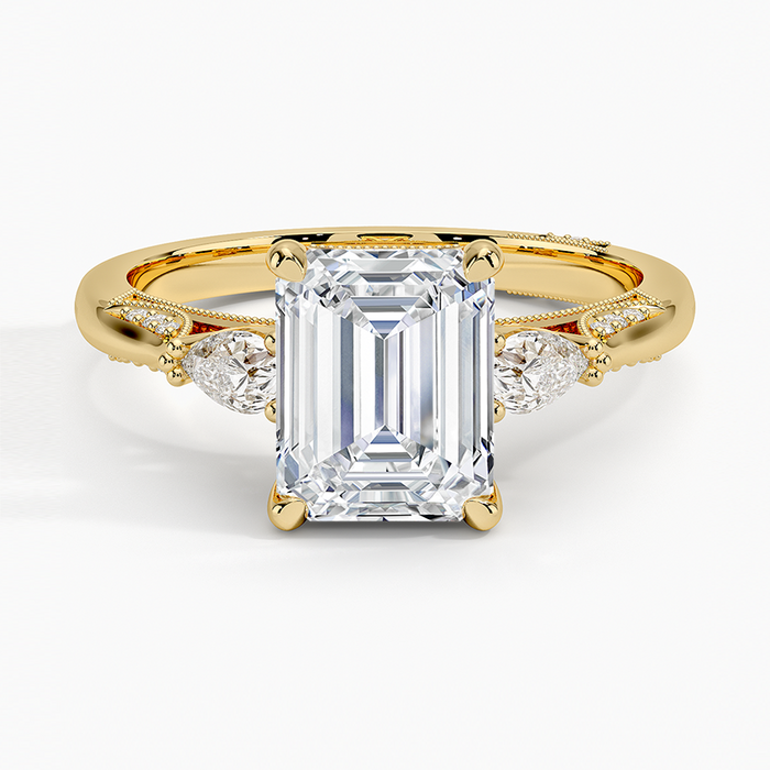 Emerald cut lab grown diamond three stone ring with pear side stones in yellow gold, top view