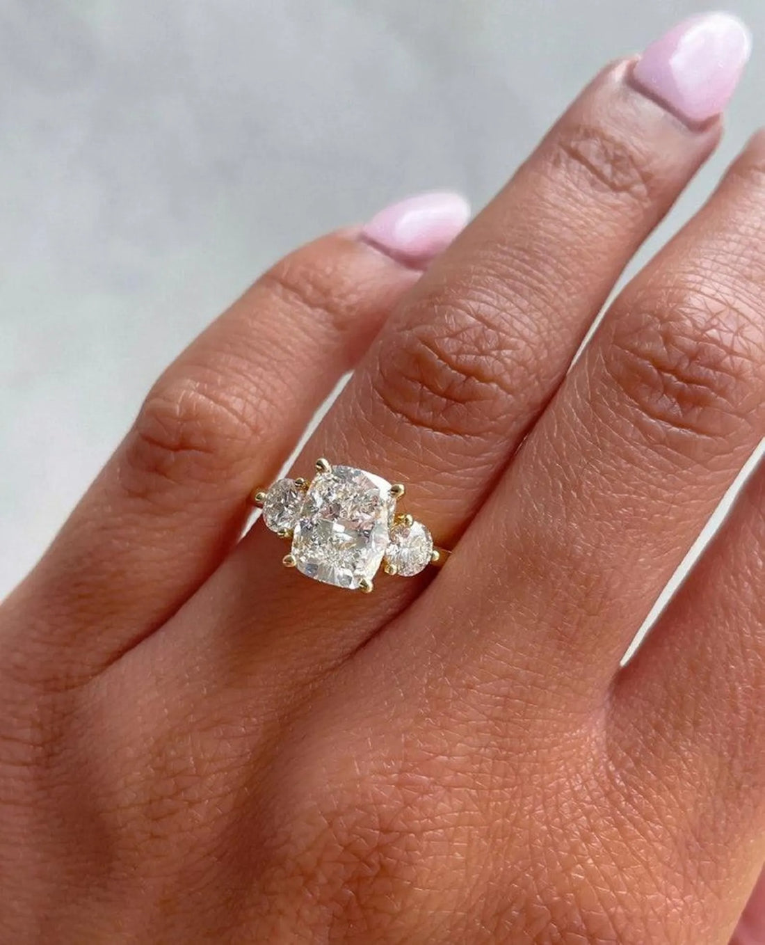 Cushion cut lab grown diamond three stone engagement ring with half moon side stones in yellow gold