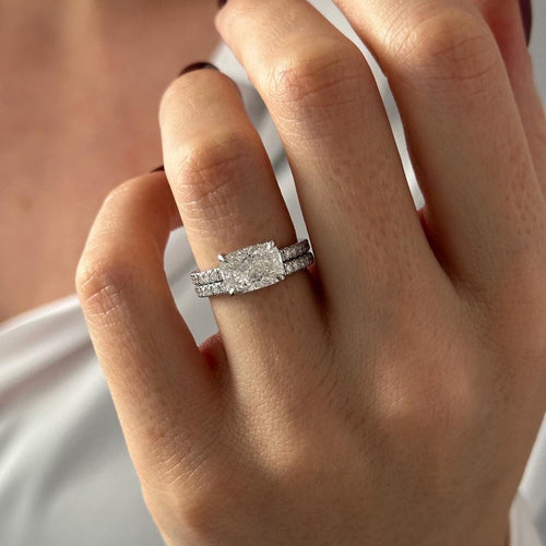 East-west elongated cushion moissanite bridal set with pave band in white gold worn on the hand