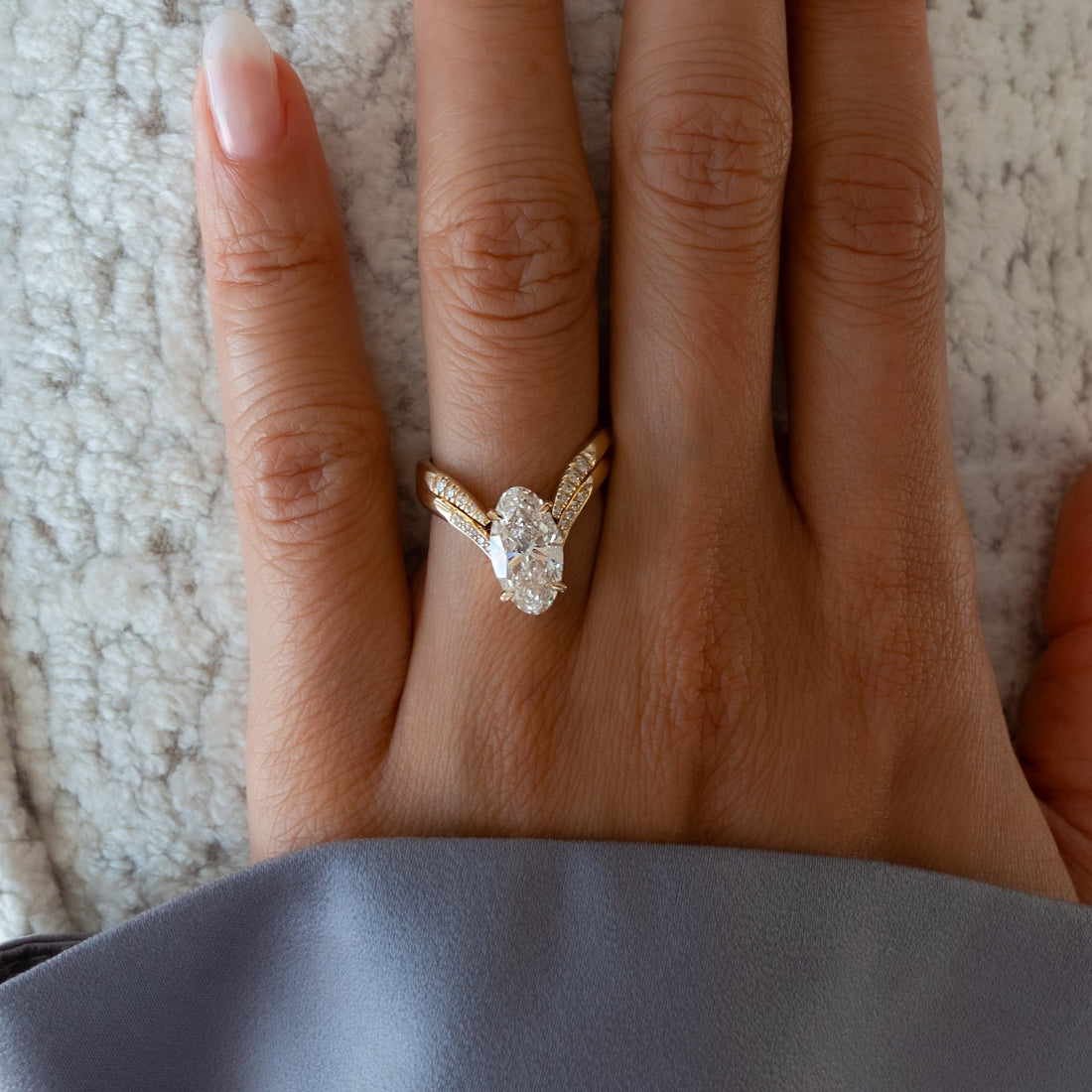 Elongated oval moissanite pave V shank bridal set with chevron band in yellow gold on the hand