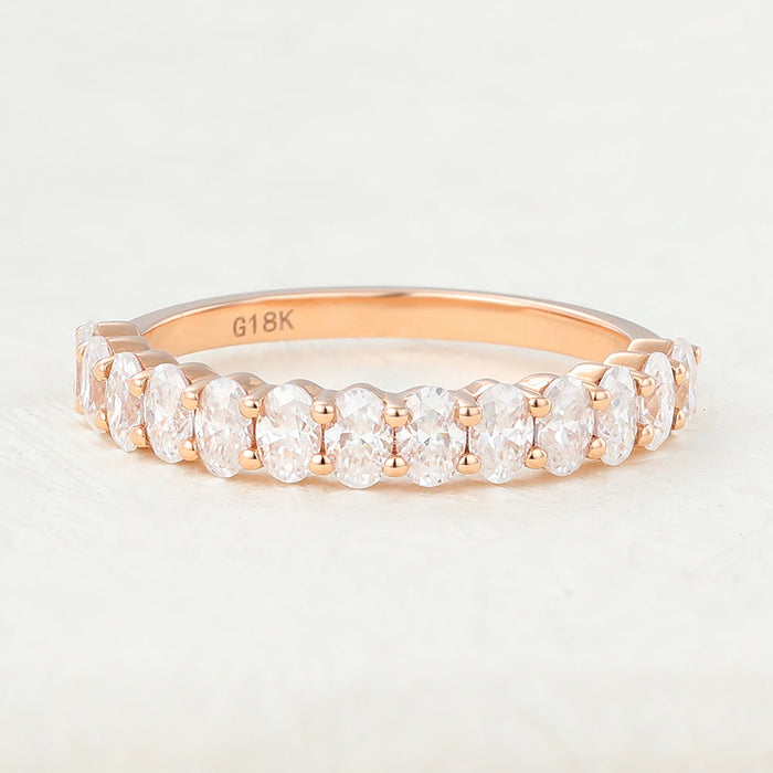 Front view of an oval moissanite half eternity wedding band in rose gold with prong set stones