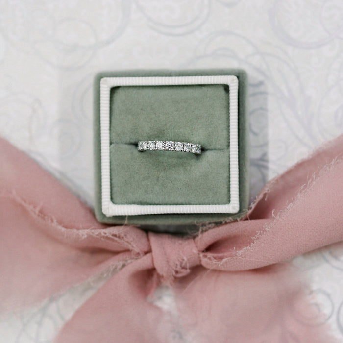 White gold scallop pave moissanite band in a green ring box with a pink ribbon
