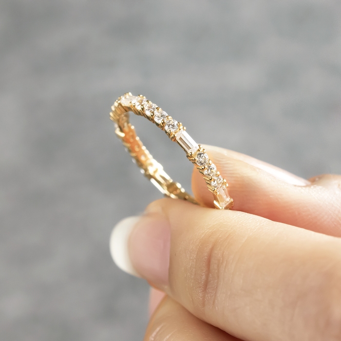 Full eternity band with alternating round and baguette moissanite held between two fingers