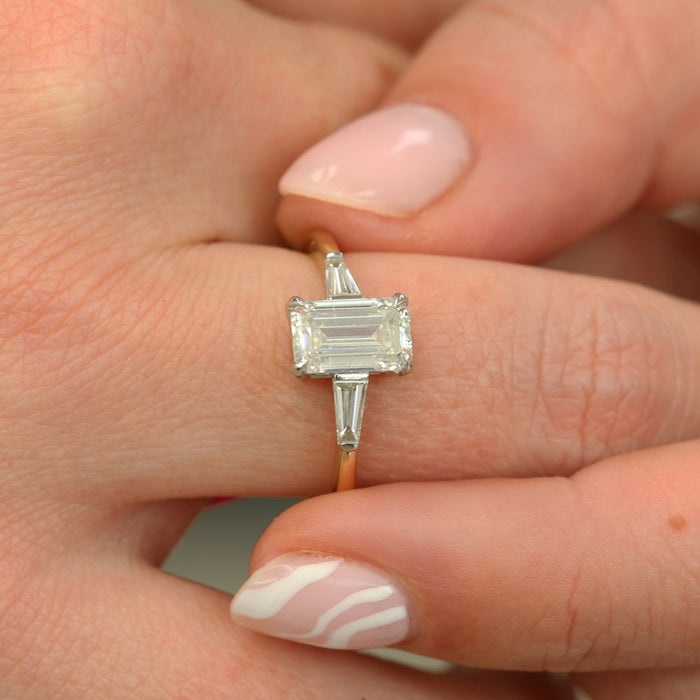 Emerald cut diamond set east west across the finger with baguettes at each side