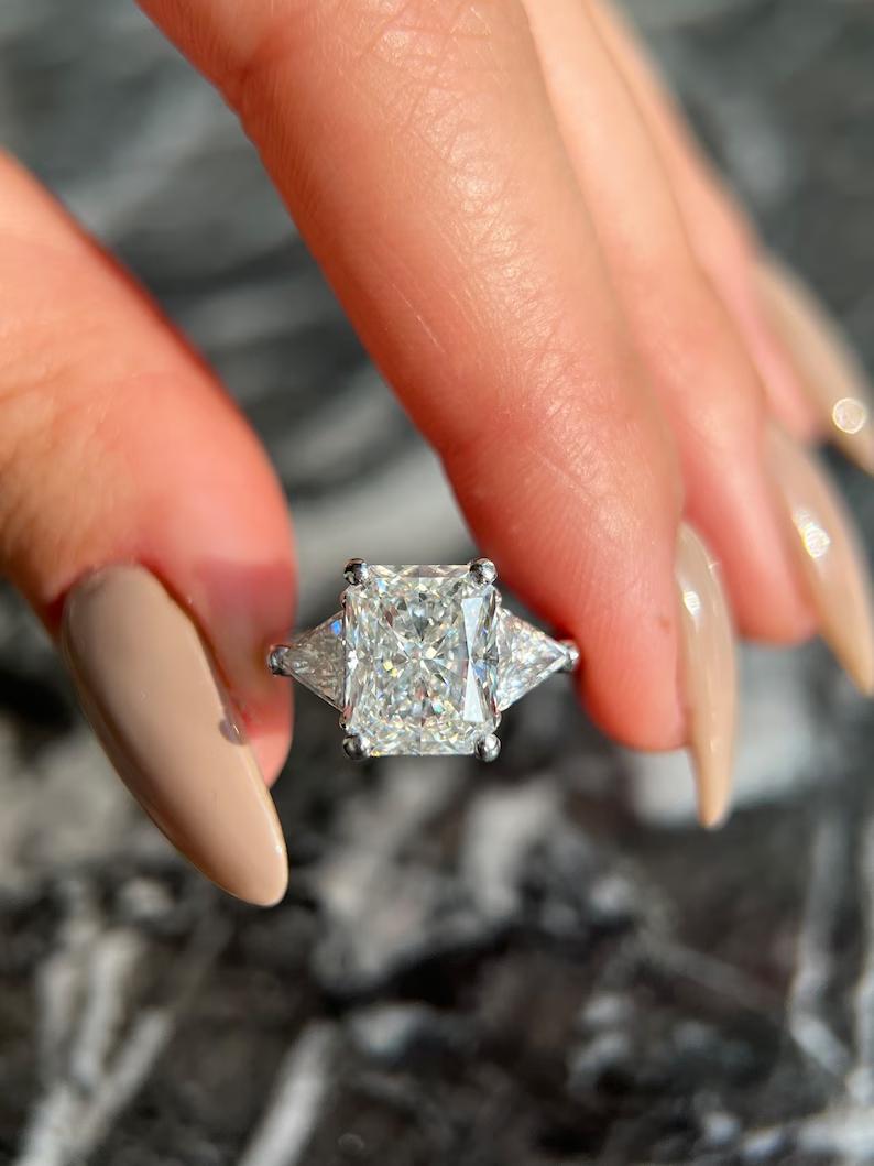 Radiant cut lab grown diamond three stone ring with trillion side stones in white metal
