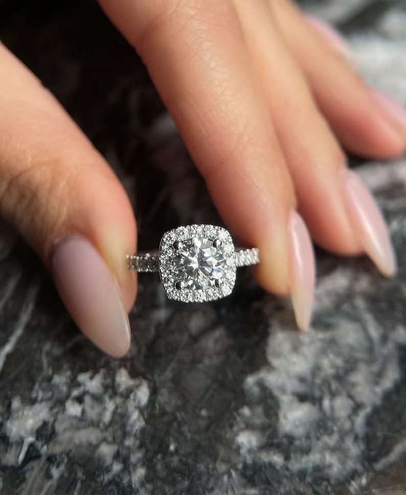 Round cut lab grown diamond in a cushion shaped halo with a pave band, worn on the hand
