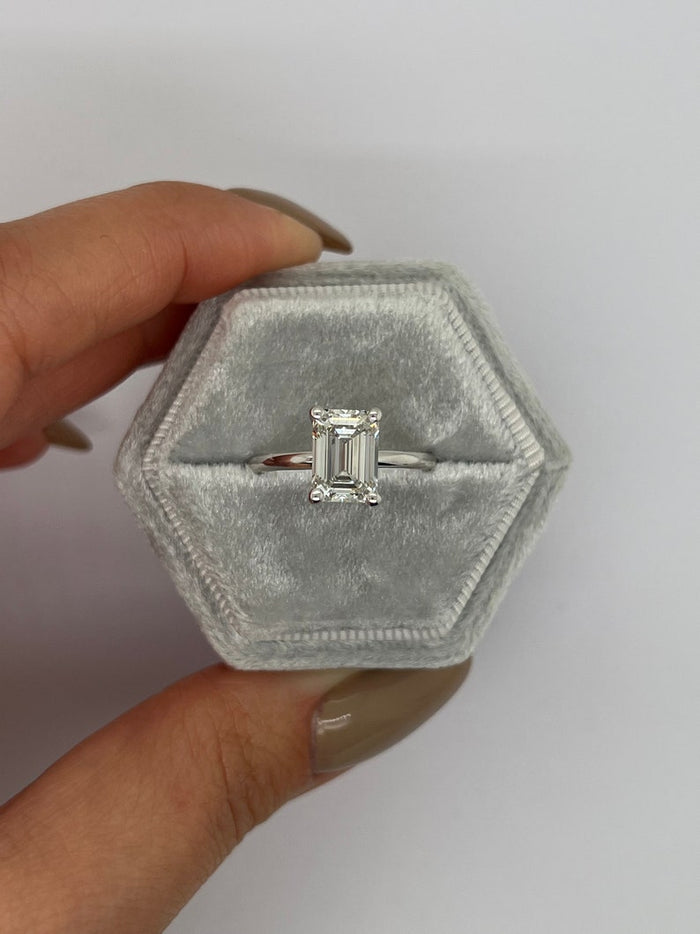 Side view of the emerald cut solitaire showing the open basket and slim shank