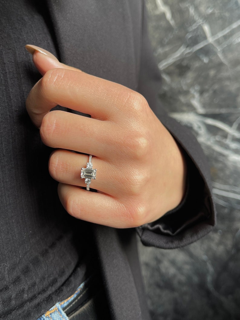 Emerald cut lab grown diamond three stone ring with round sides and a pave band