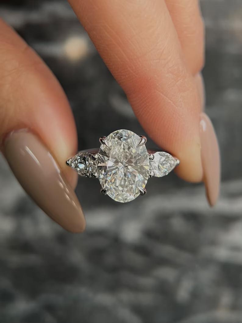 Oval cut lab grown diamond three stone ring with pear side stones in white metal
