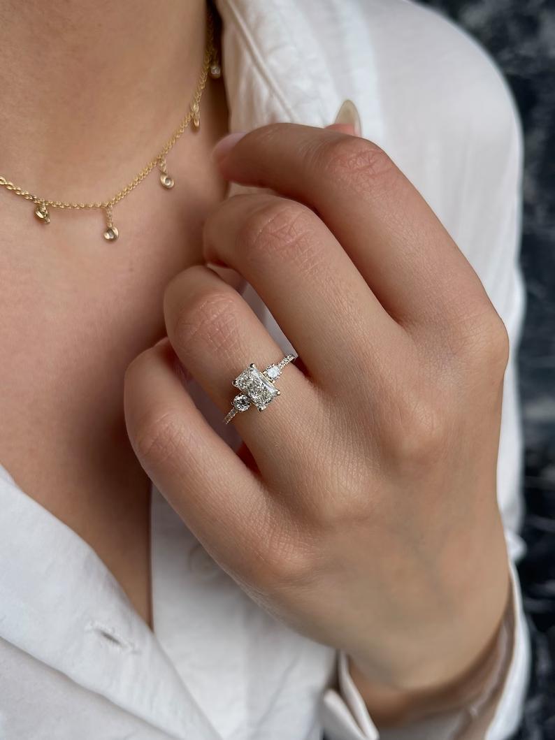 Radiant cut lab grown diamond three stone engagement ring with trillion side stones in yellow gold
