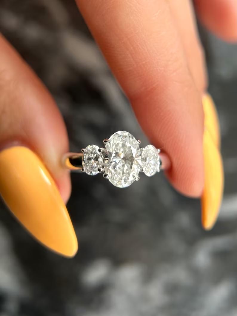 Oval cut lab grown diamond three stone ring with oval side stones in white metal