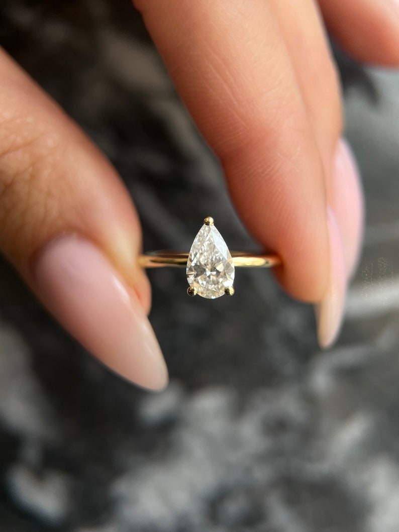 Pear cut lab grown diamond solitaire ring in yellow gold on a thin plain band