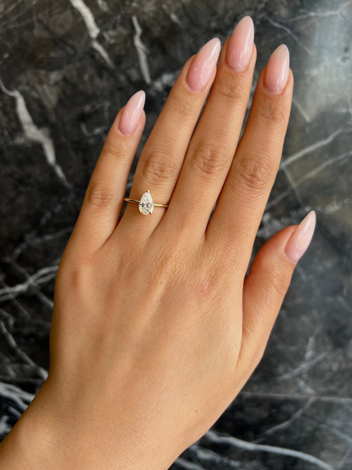 Pear cut lab grown diamond engagement ring worn on the hand