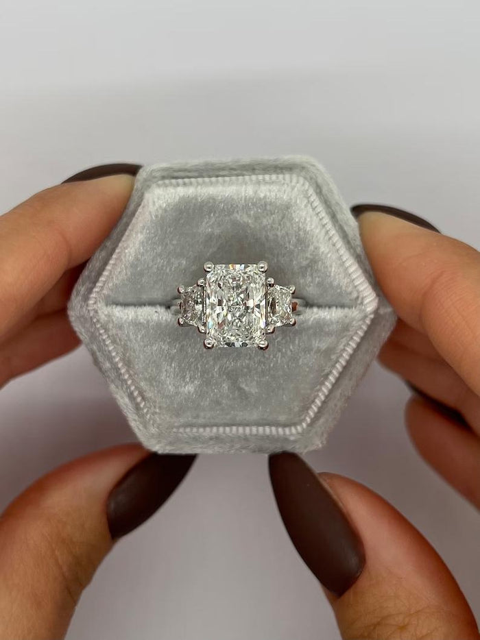 Radiant three stone engagement ring worn on the finger