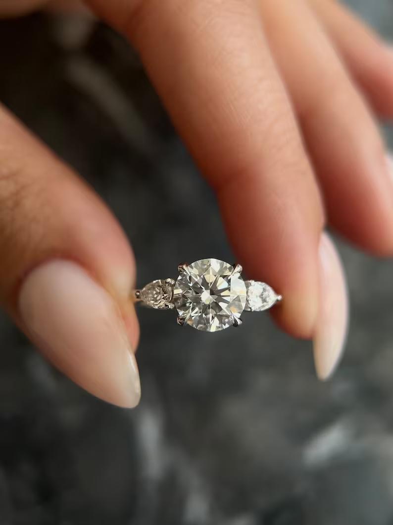 Round cut lab grown diamond three stone ring with pear side stones in white metal