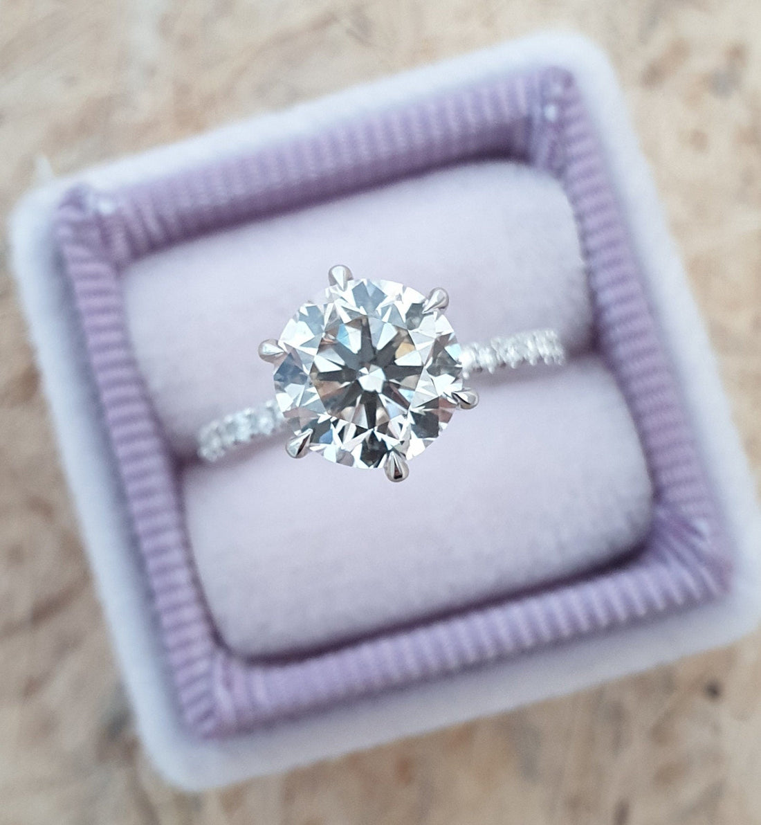 Round cut lab grown diamond solitaire ring on a pave band in white metal