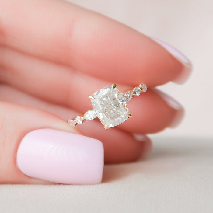 Elongated cushion cut moissanite hidden halo engagement ring in yellow gold held in hand