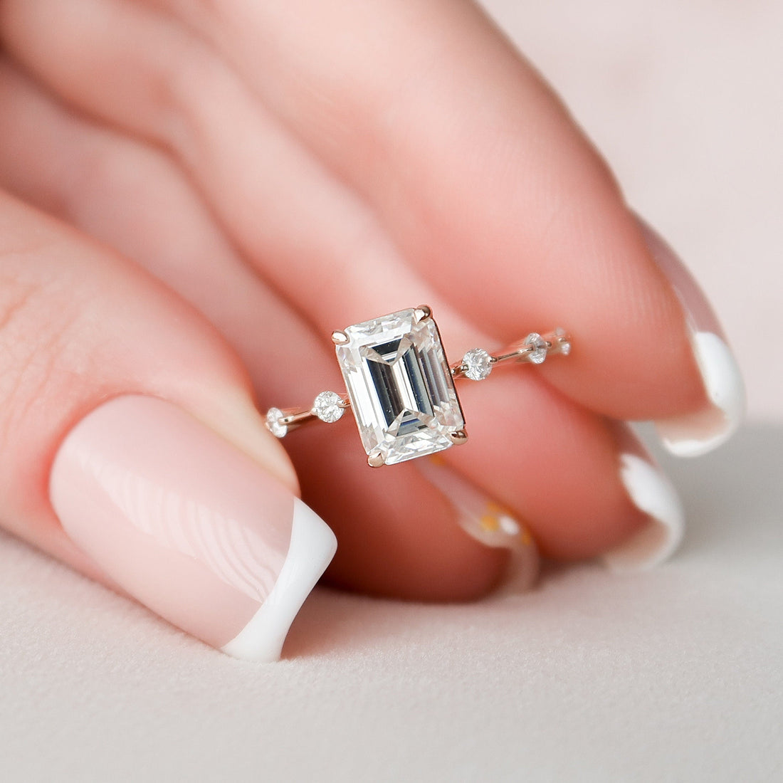Emerald cut moissanite dainty solitaire engagement ring in rose gold held in hand