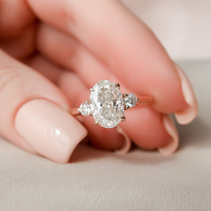 Oval cut moissanite three stone engagement ring in rose gold held in hand