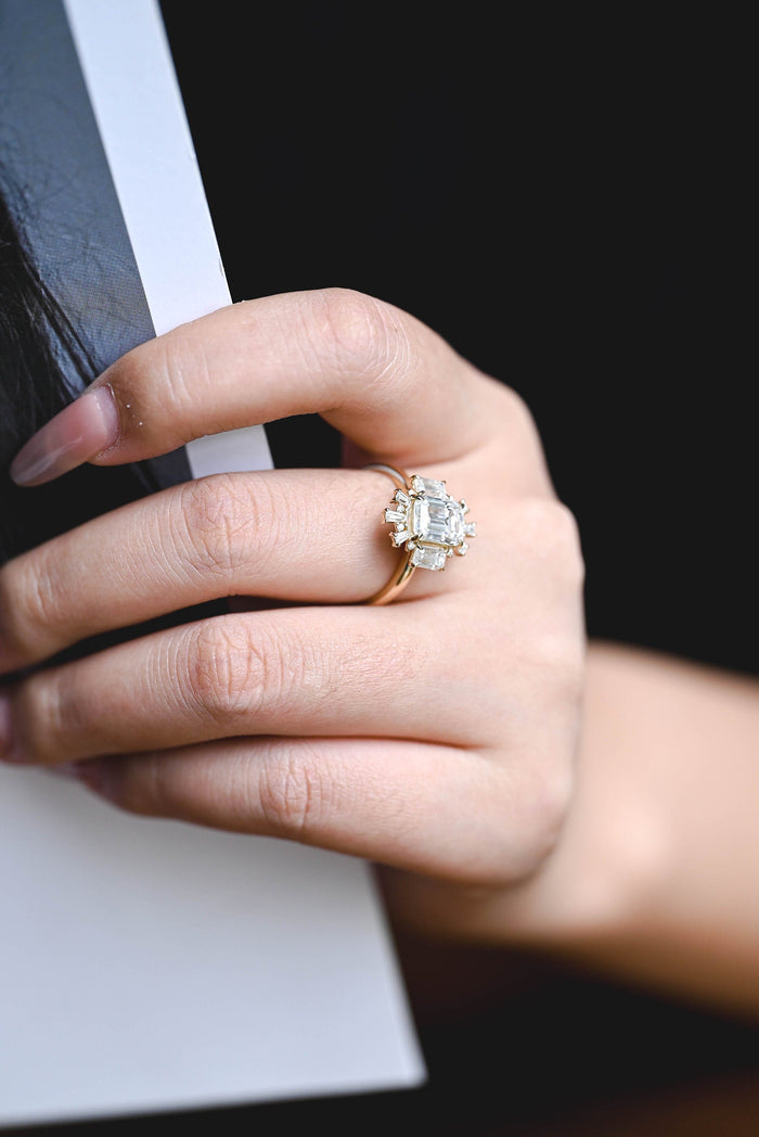 Emerald cut moissanite Art Deco sunburst engagement ring with an emerald cut on each side and a fan of tapered baguettes at the top and bottom in yellow gold, view 2